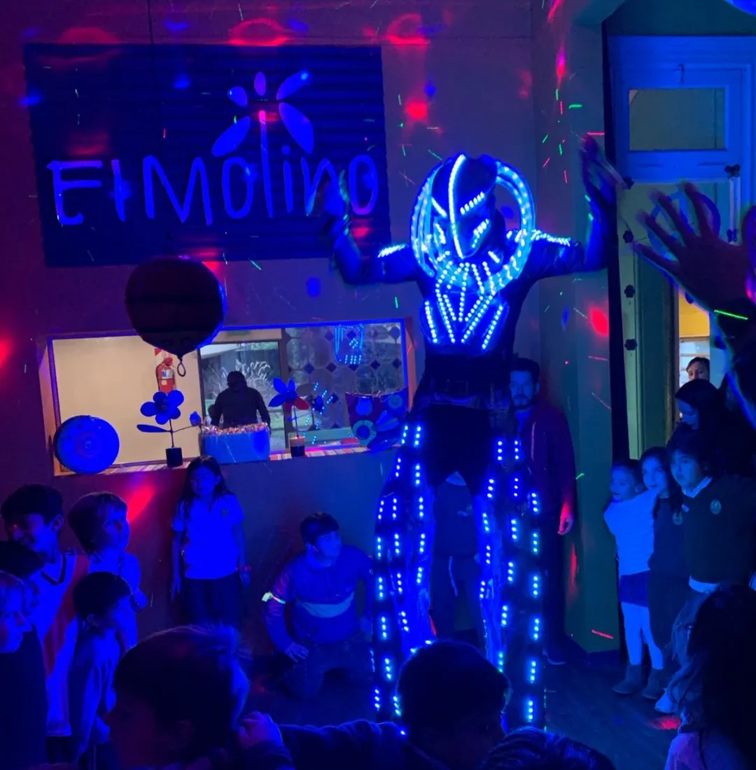 Robot de luces LED bailando con los chicos en el salón a oscuras