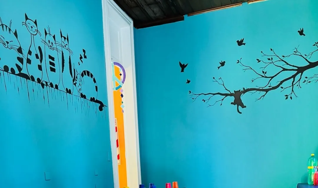 Comedor para niños con paredes turquesas y dibujos de pájaros y ramas