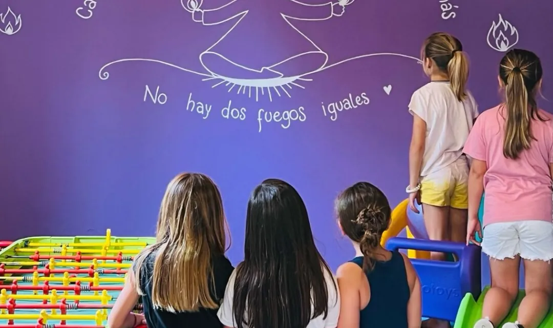 Chicas jugando en la zona blanda frente a una pared violeta ilustrada